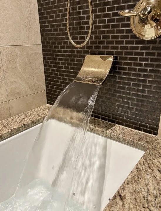 A serene bathroom scene showcasing a modern bathtub filled with water from a sleek, contemporary faucet.